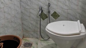 A bathroom with a toilet, a shower, and a sink. - The Grand Pratap (Dwarka)