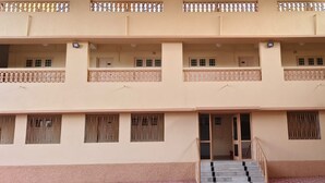 A multi-story building with balconies, windows with metal bars, and a staircase leading to the entrance. - The Grand Pratap (Dwarka)