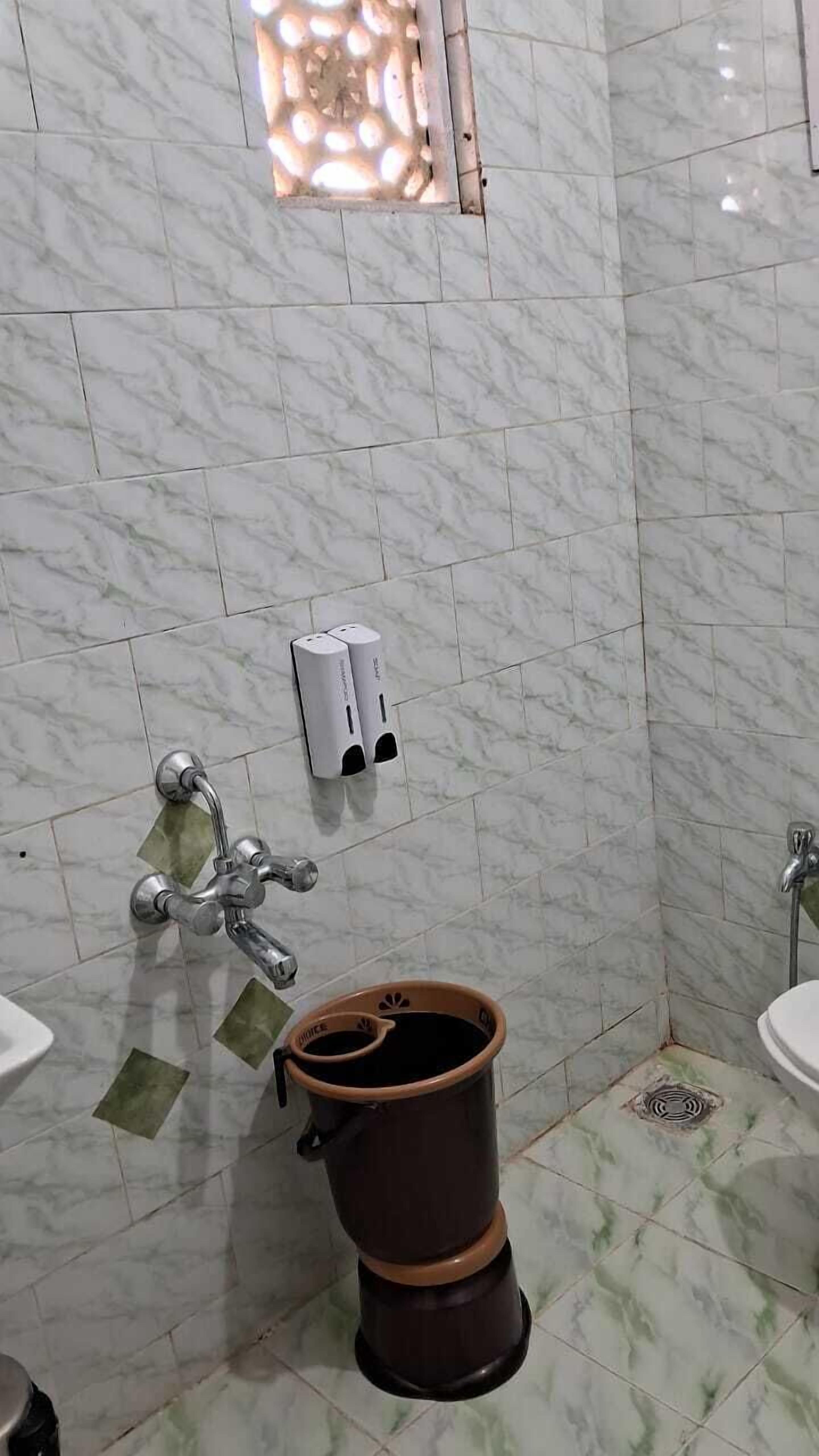 A bathroom with marble tiles, a toilet, a bidet, and a sink.
