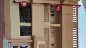 A multi-story building with a central courtyard, balconies with patterned railings, and a red fan on the second floor. - The Grand Pratap (Dwarka)