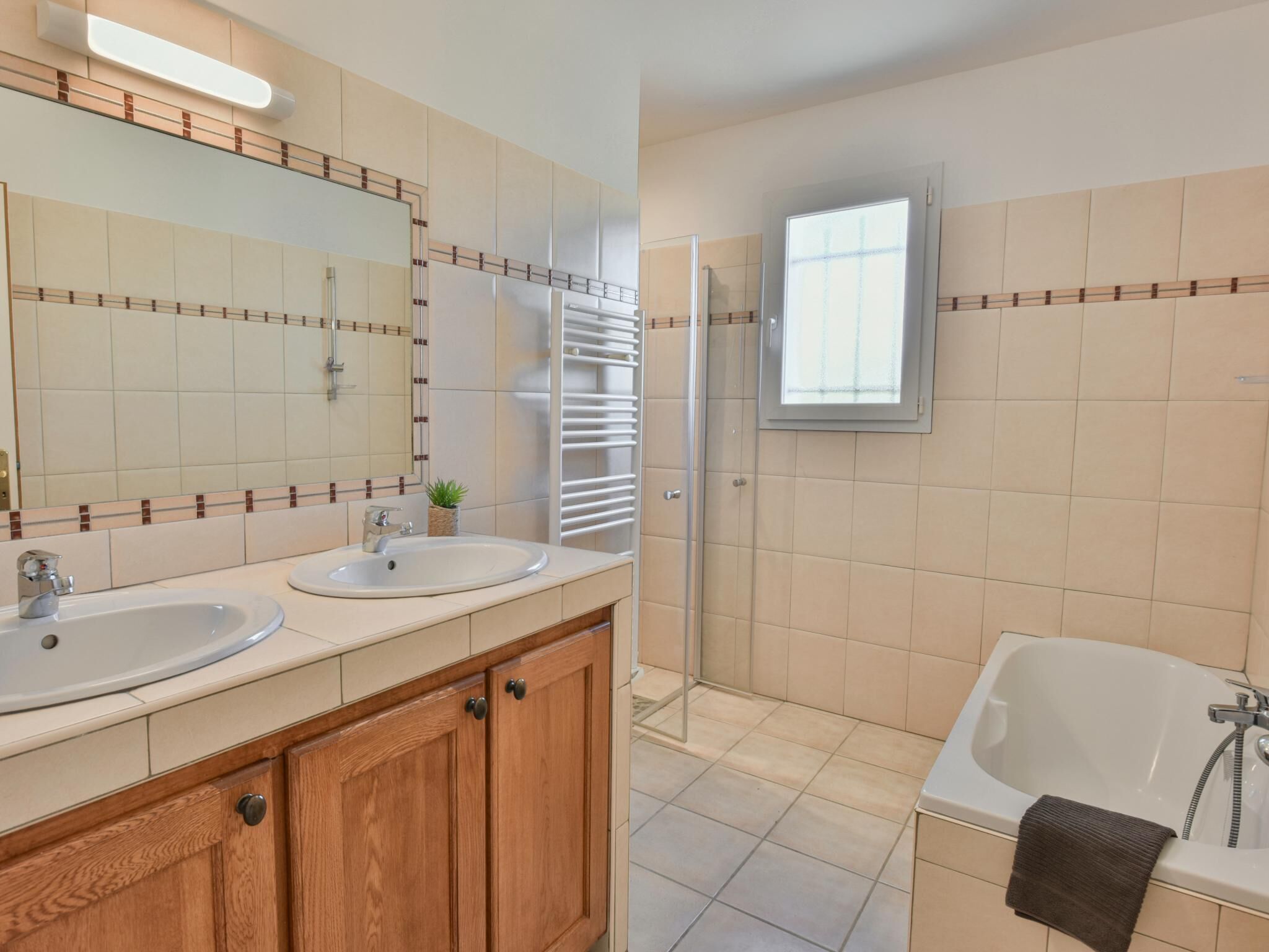 A bathroom with two sinks, a mirror, a shower, and a bathtub.