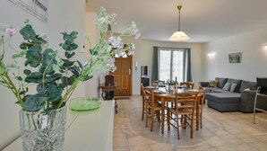 Un comedor con una mesa preparada para cuatro personas, un sofá y un televisor al fondo.