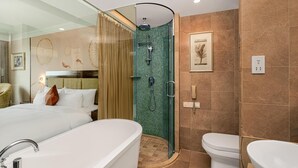 Un baño moderno con ducha de vidrio, bañera independiente y un inodoro estándar.