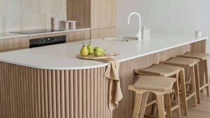 A modern kitchen with a central island, bar stools, and a sink. - The Bowen Huskisson (Huskisson)