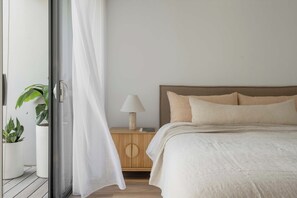 A bedroom with a bed, a nightstand with a lamp, and potted plants. - The Bowen Huskisson (Huskisson)