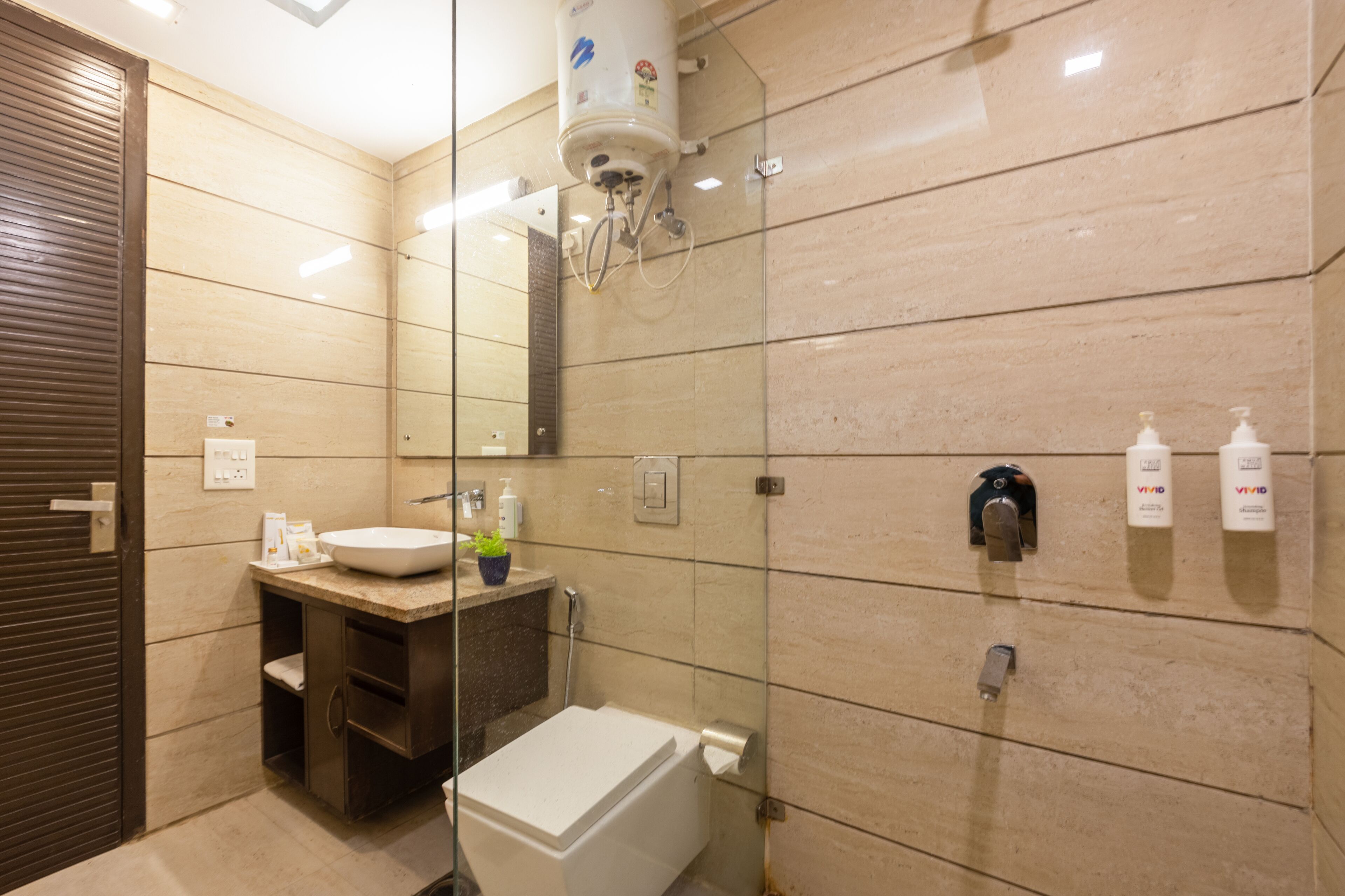 A modern bathroom with a glass shower enclosure, a white toilet, and a vanity with a sink and mirror.
