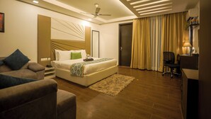 A modern hotel room with a large bed, a desk, a chair, and a sofa. - Vivid Boutique Hotel, Medanta, Gurugram (Gurugram)
