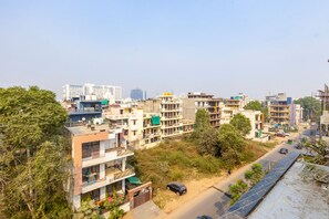 A residential area with multi-story buildings, a road with vehicles, and greenery. - Vivid Boutique Hotel, Medanta, Gurugram (Gurugram)