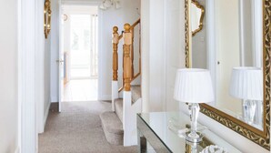 A hallway with a glass console table, a large mirror, and a chandelier. - Spacious 4-Bed Seaside Retreat in Selsey (Selsey)