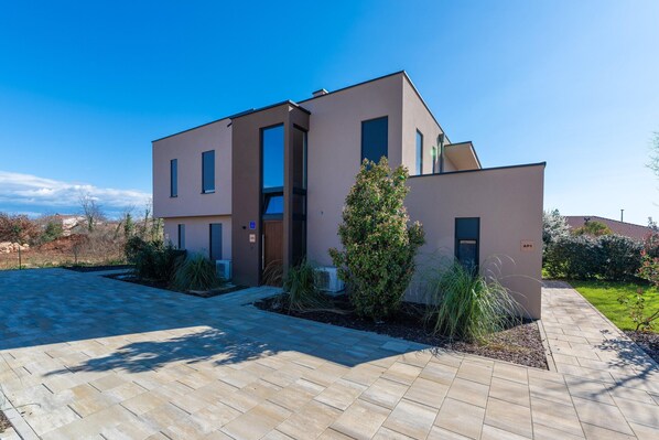 A modern two-story house with a paved driveway and a well-maintained garden. - Apartment Near Beach in Istria (Brtonigla)