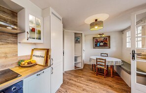 A compact kitchen with white cabinets, a wooden countertop, and a dining area with a table and chairs. - Nice home in Royan with WiFi (Royan)