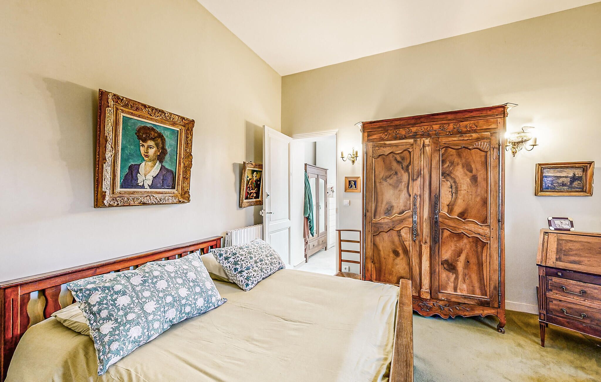 Un dormitorio con cama, armario y un cuadro en la pared.
