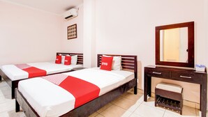 A hotel room with two single beds, a wooden dresser, a mirror, and a small bench. - Collection O Simpang Lima Near Simpang Lima Semarang Formerly Hotel Eben Haezer (Semarang)