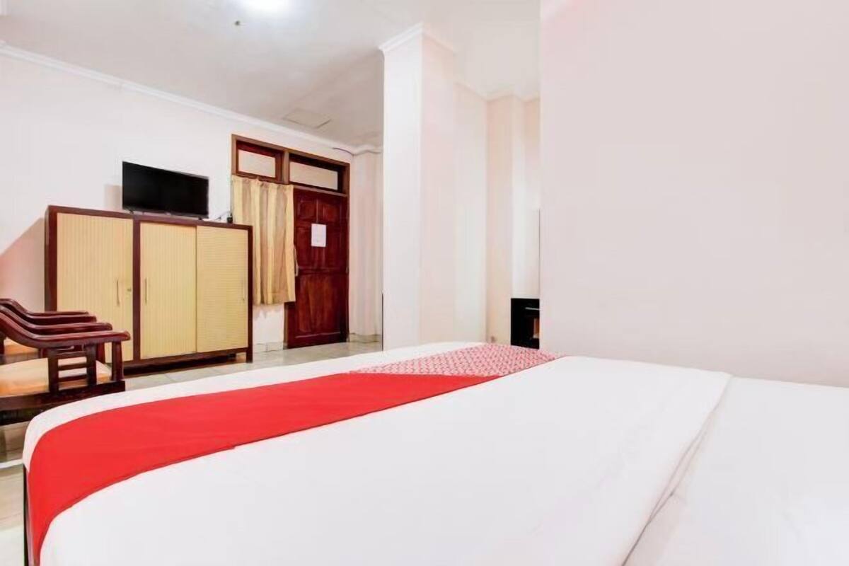A hotel room with a bed, a TV, a wardrobe, and a desk.