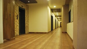 A long, narrow hallway with wooden flooring and doors on both sides. - Hotel Vijya laxmi Rooms and Banquet Hall (Surat)