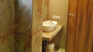 A bathroom with a marble wall, a wooden door, and a white sink. - Hotel Vijya laxmi Rooms and Banquet Hall (Surat)