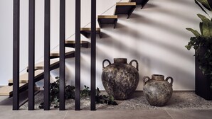 A staircase with wooden steps and black railings, accompanied by two rustic vases and a potted plant. - Estelle Villa, a Flamboyant Escape (PRWP+7J Mouzaki, Greece)