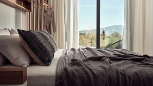 A bedroom with a large bed, a wooden headboard, a view of the outdoors, and a balcony. - Estelle Villa, a Flamboyant Escape (PRWP+7J Mouzaki, Greece)