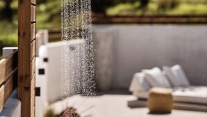 A modern outdoor shower with a wooden frame, a pool, and a seating area with cushions. - Estelle Villa, a Flamboyant Escape (PRWP+7J Mouzaki, Greece)