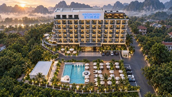 A hotel with a pool, surrounded by lush greenery and a view of mountains. - Kinton hotel (Vang Vieng)