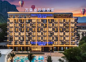 A multi-story hotel with a modern facade, balconies, and a swimming pool area. - Kinton hotel  (Vang Vieng)