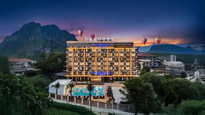 Een hotel met meerdere verdiepingen, een zwembad en een bergachtige achtergrond.