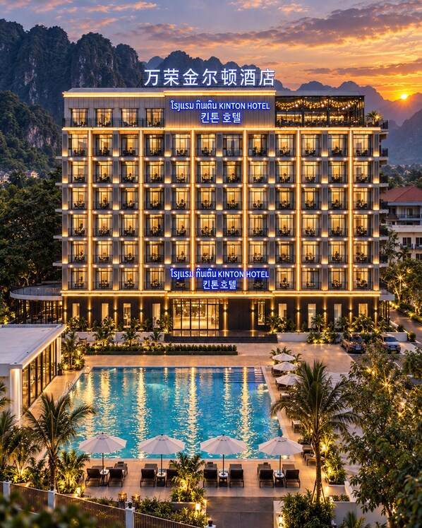 A hotel with multiple floors, a swimming pool, and outdoor seating areas.
