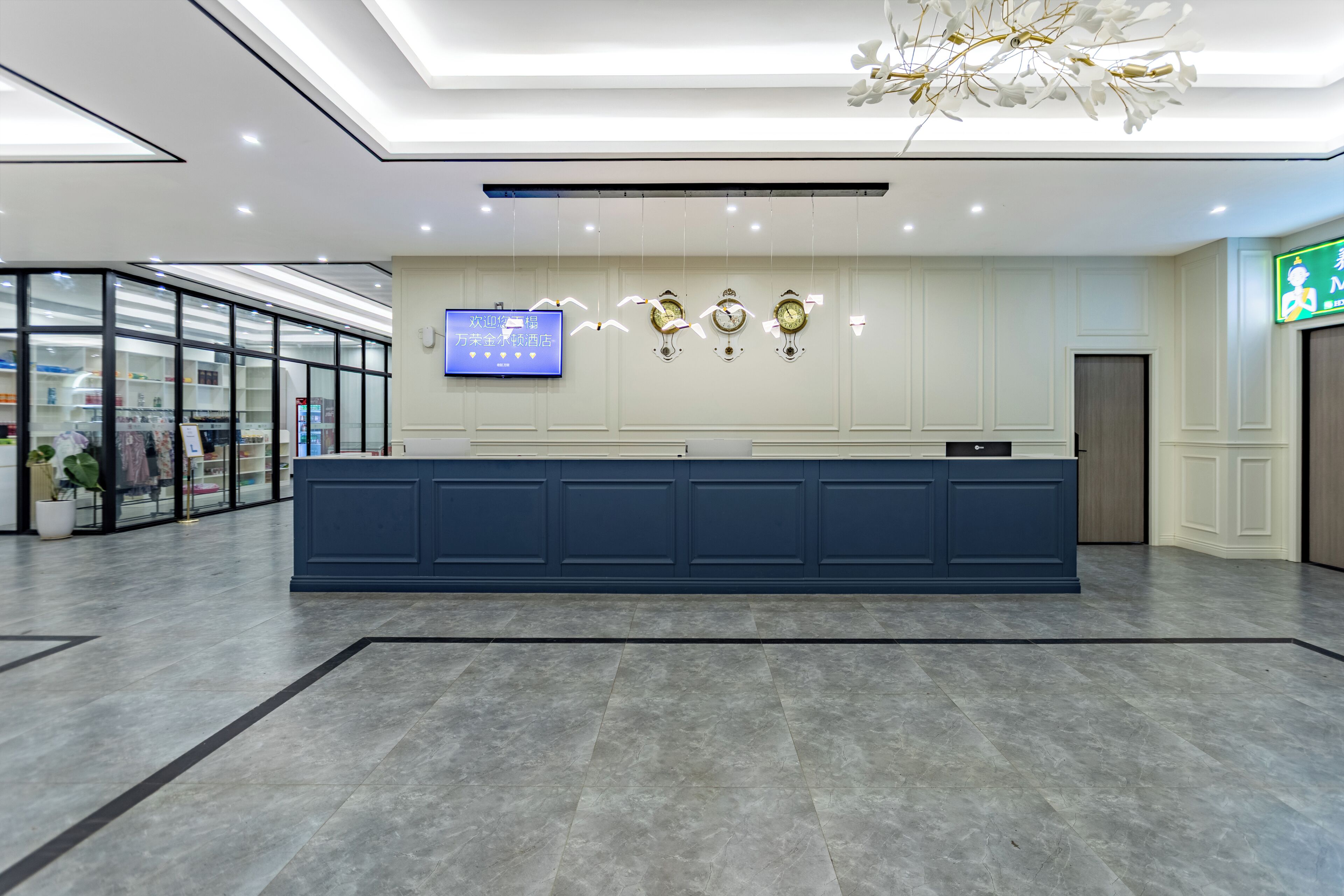 Una moderna zona de recepción con un mostrador azul, una pantalla digital y tres relojes de pared.