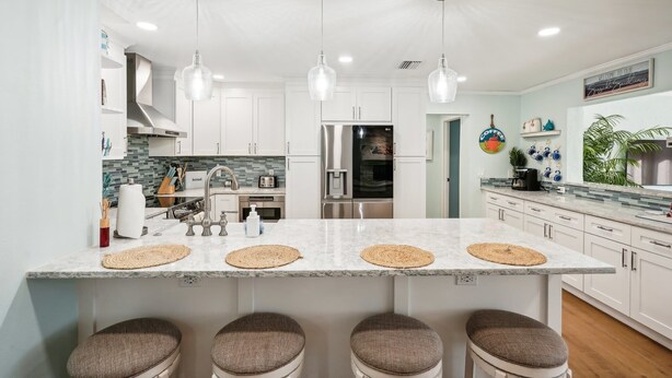 A modern kitchen with a large island, stainless steel appliances, and pendant lighting.