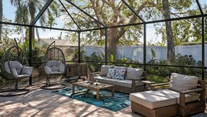 A covered patio with a wooden table, cushioned chairs, and a sofa.