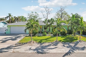A residential property with a green house, a well-maintained lawn, and palm trees. - 4 Br Bradenton Home~Private Pool, Outdoor Bar, W/D (Bradenton)