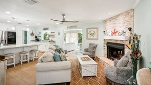 A modern living room with a fireplace, a kitchen area, and a dining space.