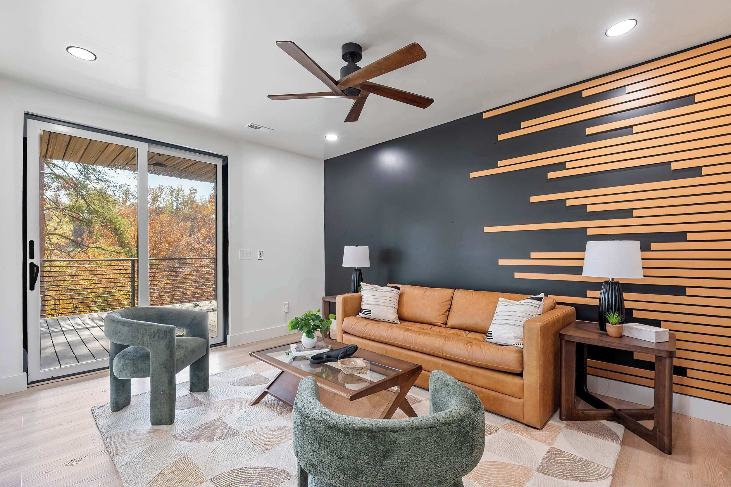 A modern living room with a sofa, two chairs, a coffee table, and a ceiling fan.