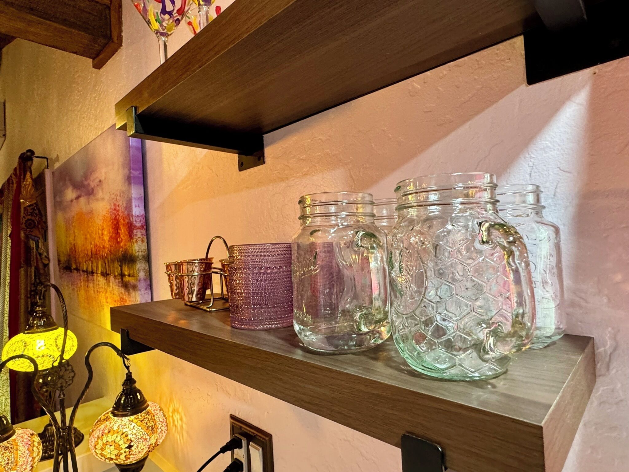 Una estantería con frascos de vidrio, un candelabro y una lámpara decorativa.