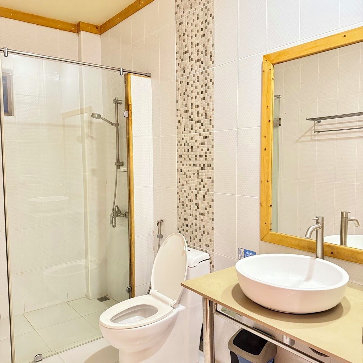 Ein Badezimmer mit Duschkabine, Toilette und Waschbecken mit Spiegel darüber.