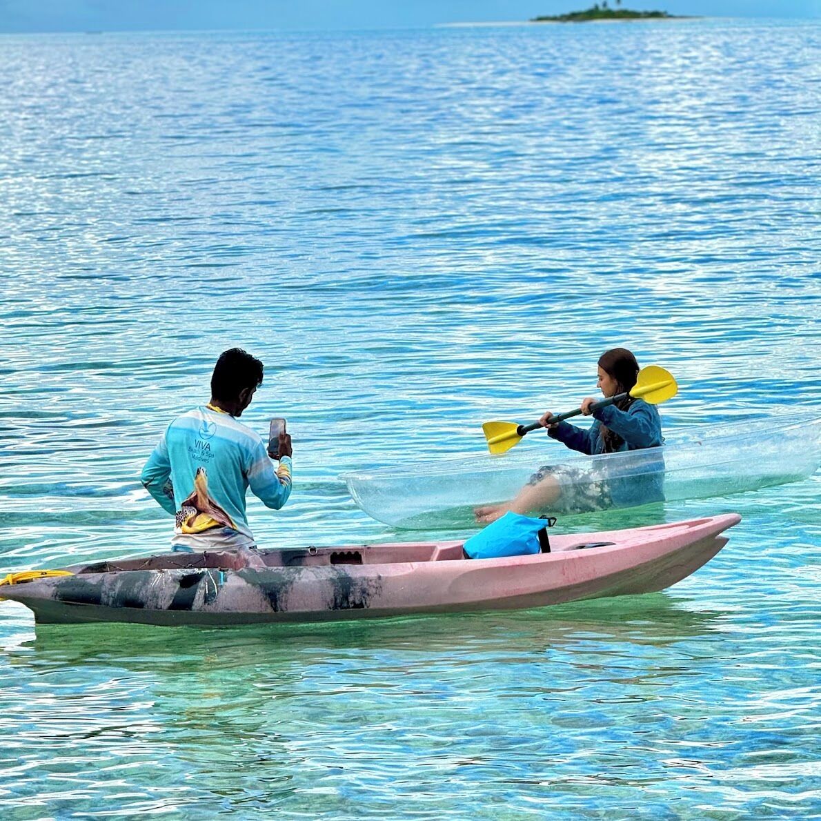 Two people kayaking on a calm body of water.