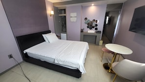 A modern hotel room with a large bed, a small desk, a chair, and a TV. - Elysee Hotel (Daegu)