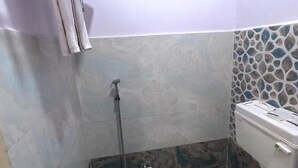 A small bathroom with a toilet, a shower, and a tiled wall.