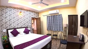A hotel room with a bed, a desk, a chair, a television, and a ceiling fan.