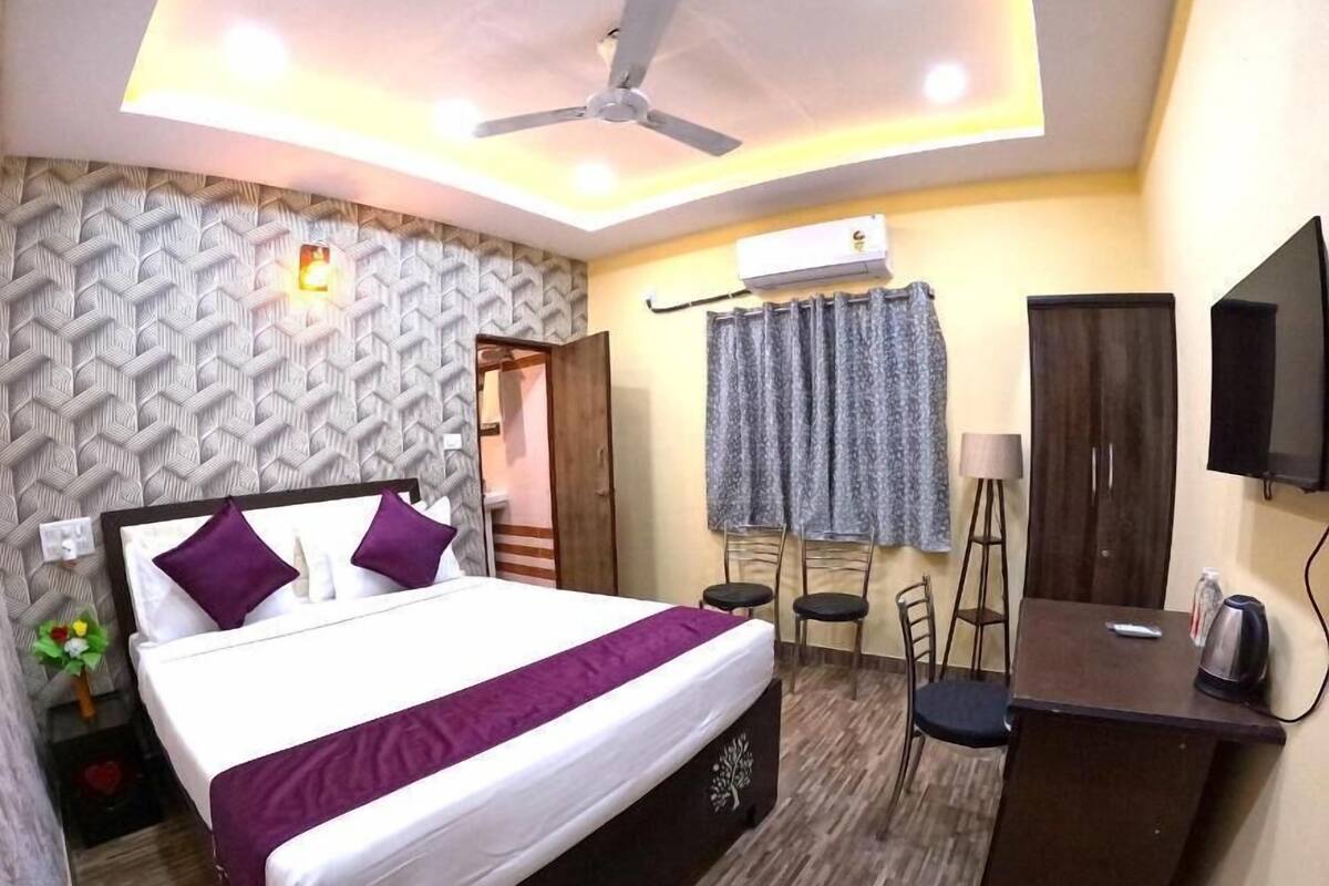 A hotel room with a bed, a desk, a chair, a television, and a ceiling fan.