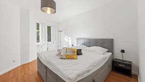 Un dormitorio con cama, mesita de noche y lámpara colgante.