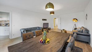 Una sala de estar moderna con una mesa de comedor de madera, sofás grises y un frutero.