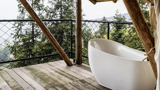 A white bathtub on a wooden deck with a view of trees and mountains. - BZIKA Wonderland Retreat (Zhangjiajie)