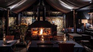 A cozy restaurant with a stone wall, a fireplace, and wooden furniture. - BZIKA Wonderland Retreat (Zhangjiajie)