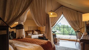 A bedroom with a large bed, a sitting area with a table and chairs, and a balcony with a view of the outdoors. - BZIKA Wonderland Retreat (Zhangjiajie)
