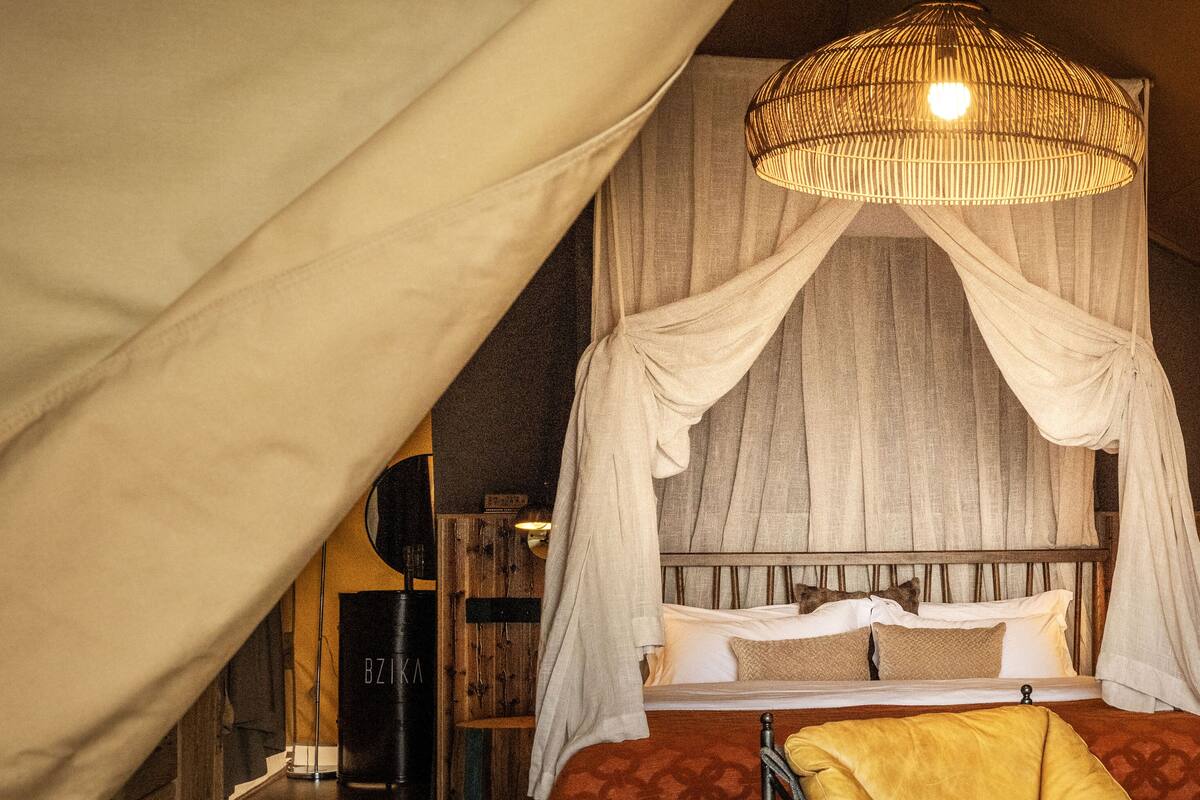A cozy bedroom with a canopy bed, a hanging light fixture, and a small stool.