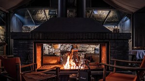 A cozy fireplace area with a stone wall, a fire burning, and leather chairs. - BZIKA Wonderland Retreat (Zhangjiajie)