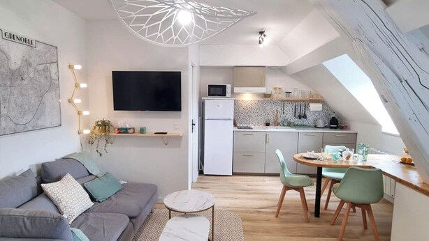 A modern apartment with a living room, kitchenette, and dining area.