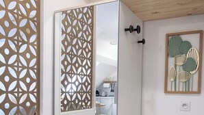A modern room with a white wardrobe, a decorative screen, and a framed artwork on the wall.