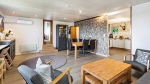 Un espai de vida modern amb zona de menjador, cuina i escala que condueix a un nivell superior.